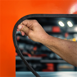 Hand showing Edge Trim being installed on an orange metal panel